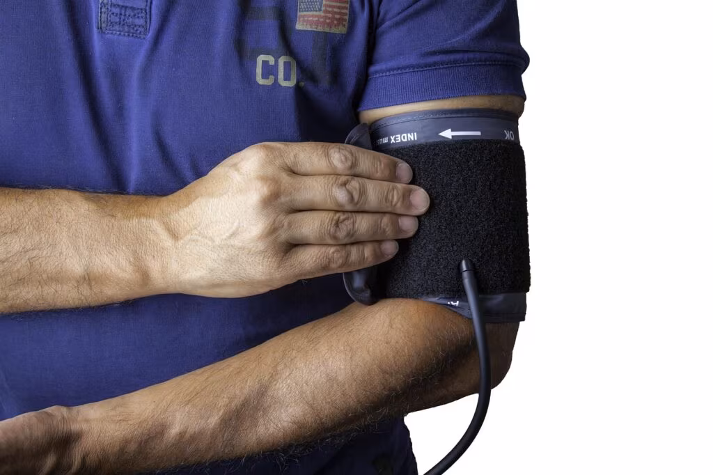 A person using a digital blood pressure monitor on their arm, focusing on hypertension management