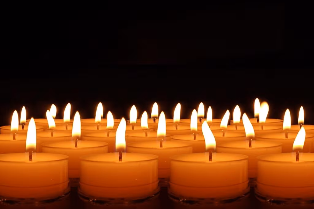 A single candle burning brightly in a dark setting, symbolizing remembrance and loss.