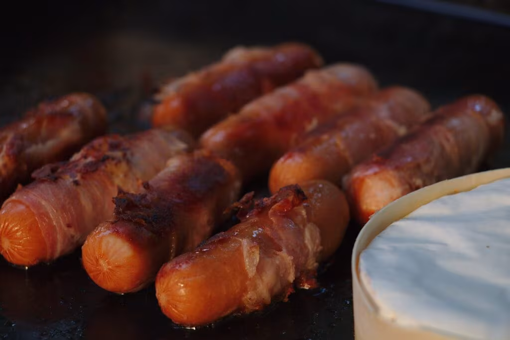 Assortment of ultra-processed foods including packaged deli meats, bacon, and sugary soft drinks.