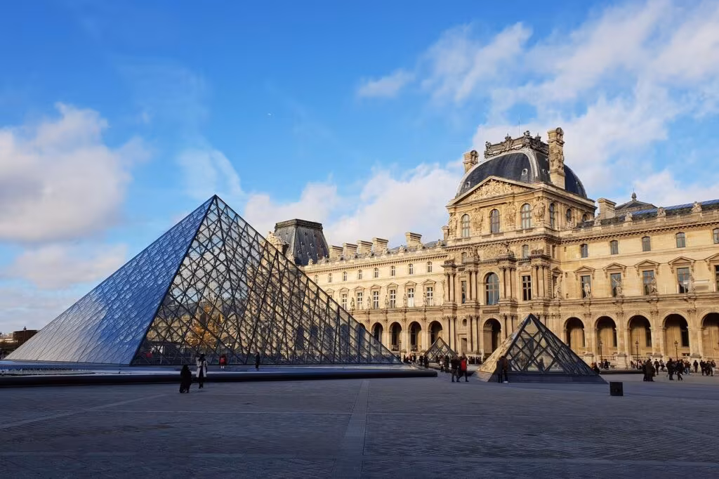Exterior view of the Louvre Museum in Paris with the glass pyramid, symbolizing high-security cultural institution.