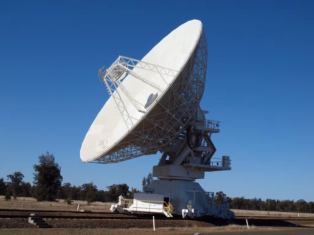 Large satellite dish tracking system against a dark night sky, symbolizing space surveillance