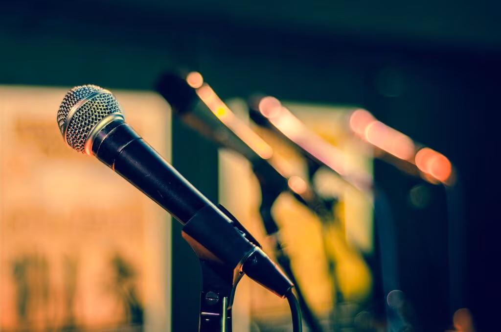 Reba McEntire sitting in her coach's chair on The Voice stage, looking reflective.
