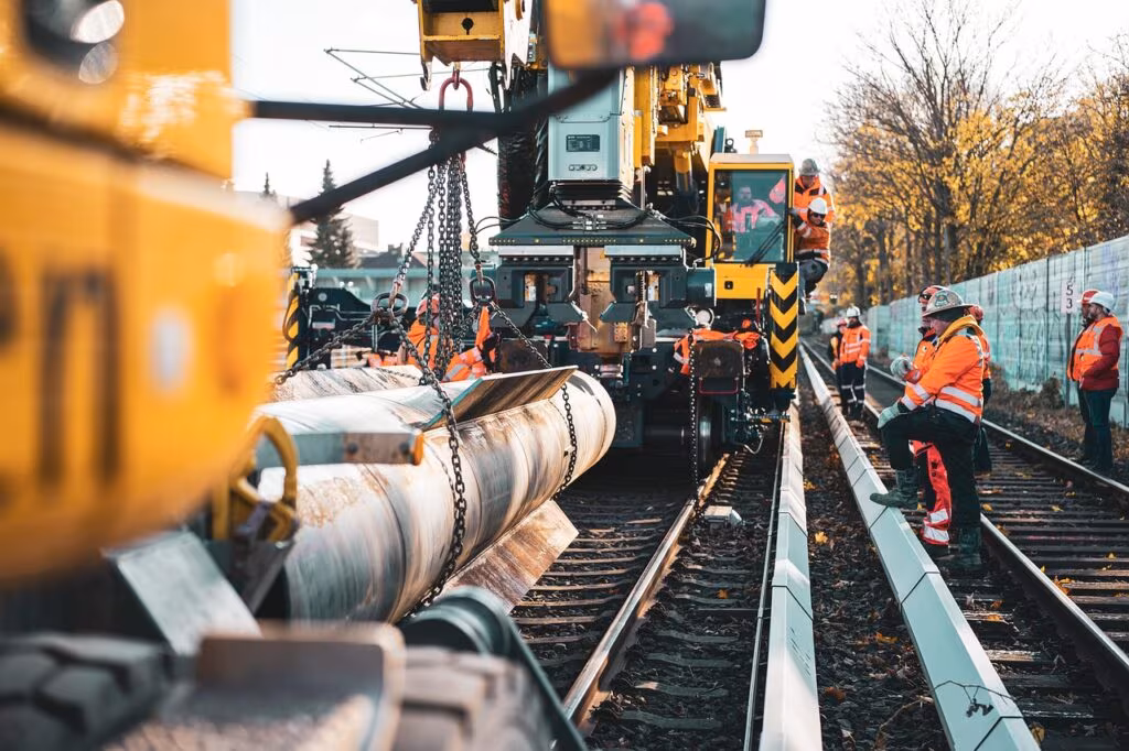 Two men dressed as construction workers moving a large object on a New York City street.