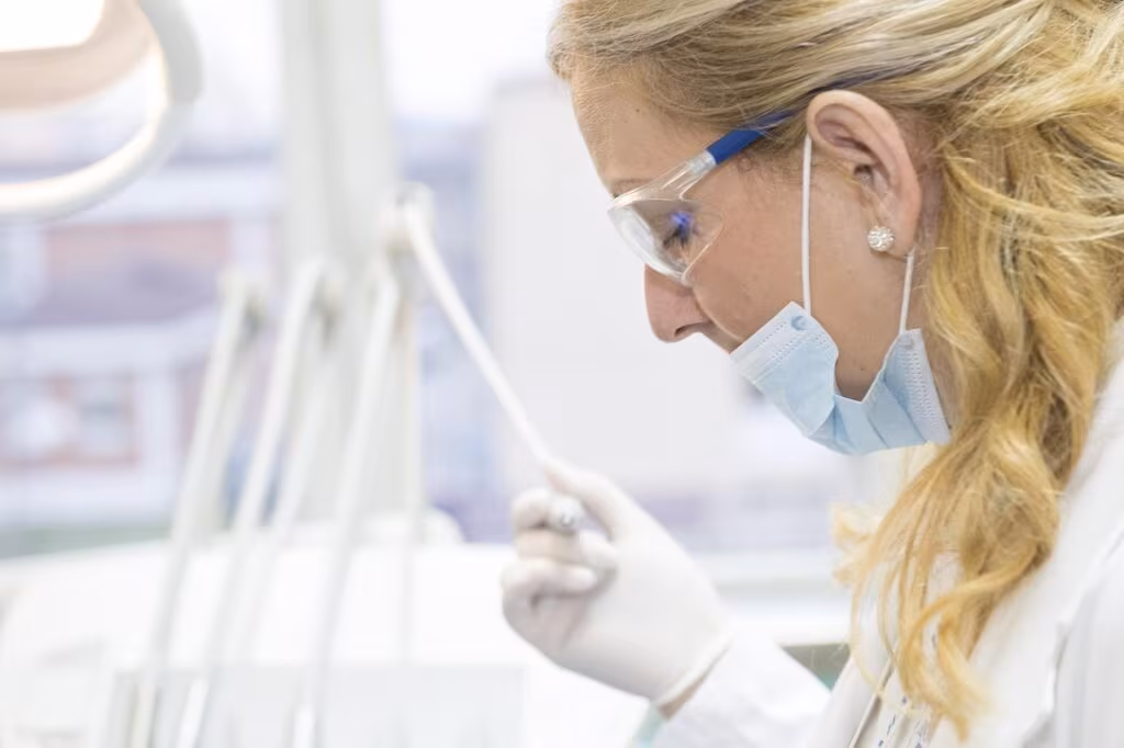 A doctor speaking with a patient in an examination room, taking notes on a clipboard.