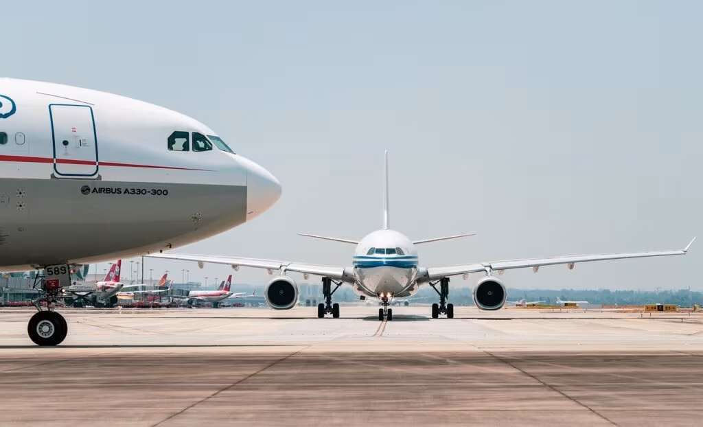 A large commercial jet taking off from a modern airport runway against a blue sky.