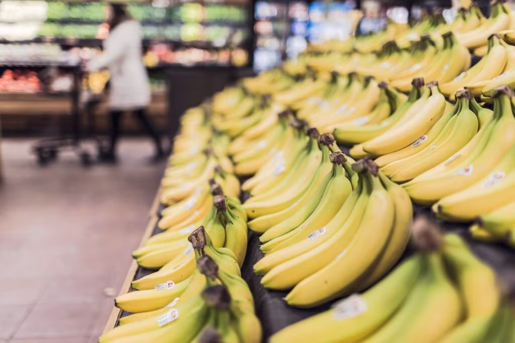 A parent and child selecting fresh produce in a supermarket, using food assistance funds.