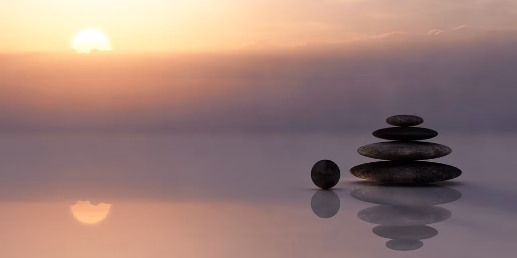 A person meditating outdoors at sunrise, symbolizing health, wellness, and stress management.