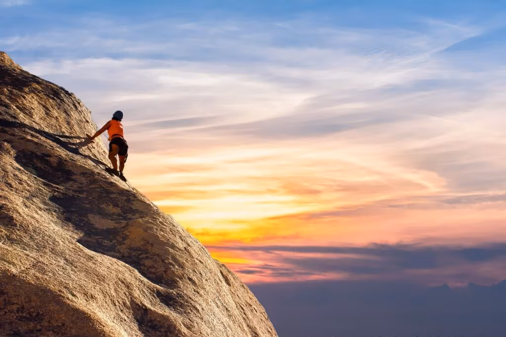 A person standing determinedly on a mountain peak at sunrise, symbolizing courage and facing challenges.