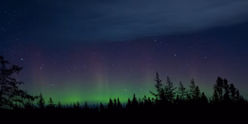 A photograph of the Northern Lights displaying both green and rare blue colors high in the night sky.
