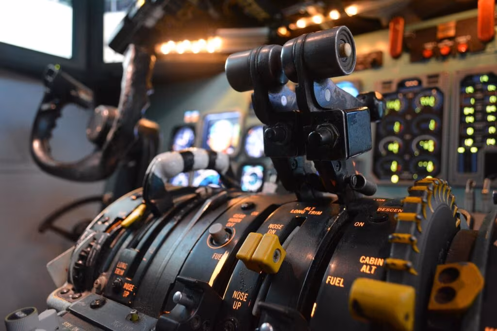 A racing simulator setup showing a Gran Turismo game on a large screen with a steering wheel and pedals.