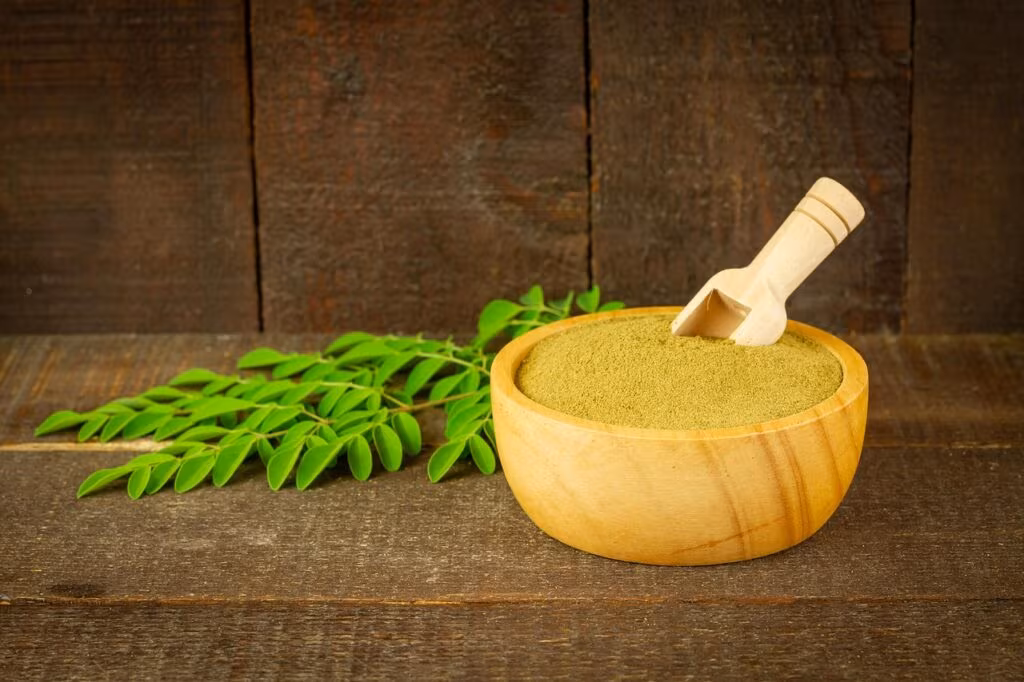 A scoop of white creatine monohydrate powder next to a supplement container.