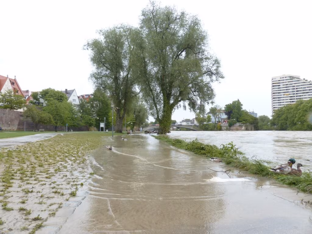 A village partially submerged in floodwaters, showing the destruction and harm caused by extreme weather events.