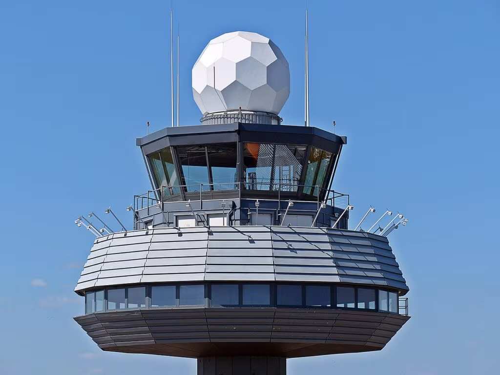 Air traffic control tower overseeing a busy airport runway with multiple commercial and private aircraft