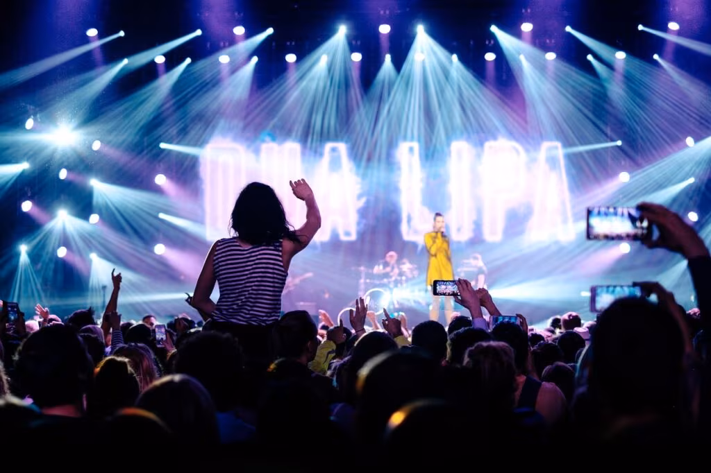Ariana Grande performing on stage with a microphone, capturing the energy of the concert special.