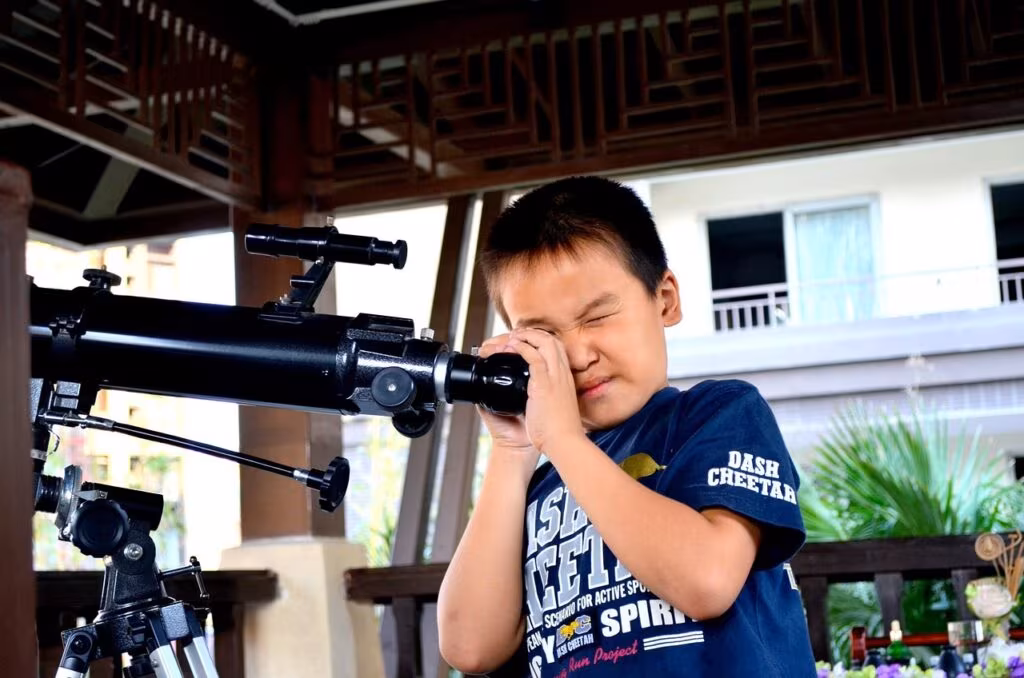 Astronomer looking through a large optical telescope at night in an observatory dome