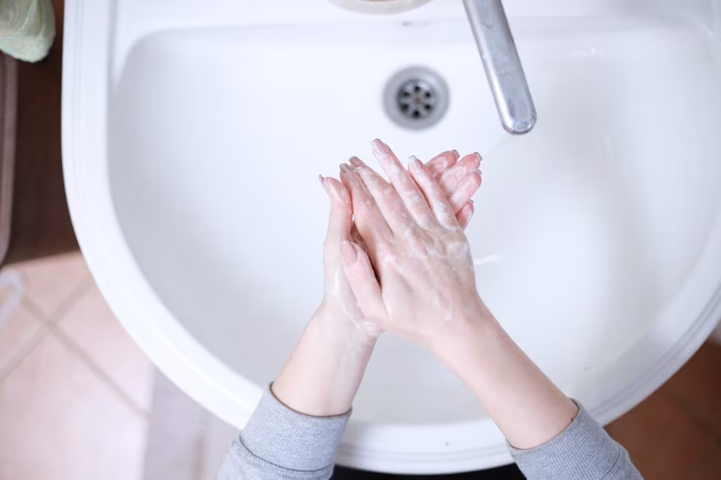 Close-up of hands thoroughly washing with soap and water under a faucet.