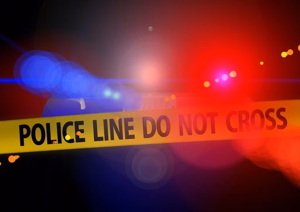 Close-up of several fired bullet casings scattered on the ground, marked as evidence at a crime scene.