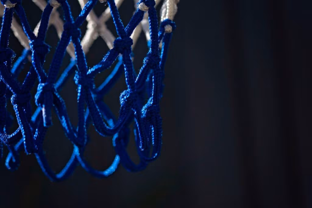 College basketball coach intensely watching the game from the sideline, giving instructions.