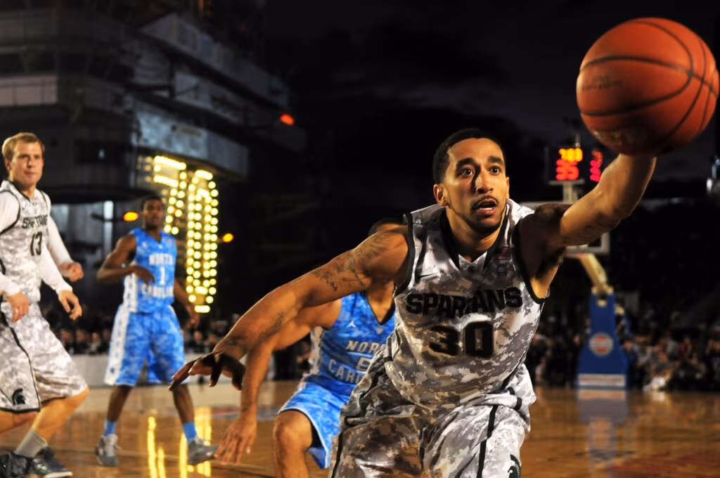 College basketball players fighting for a defensive rebound during a high-stakes game.