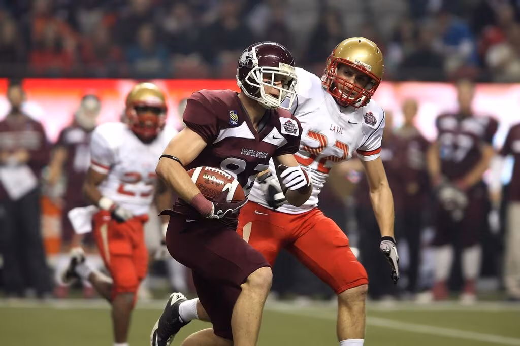 College football player in uniform running with the ball during a game.