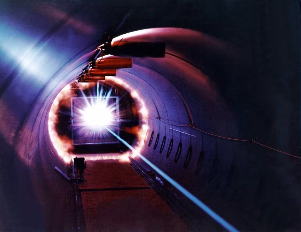 Conceptual diagram showing a laser beam traveling down a fiber optic cable to vaporize a block of ice, creating a borehole