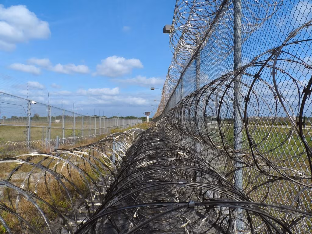 Exterior view of a federal correctional institution with high fences and security measures.