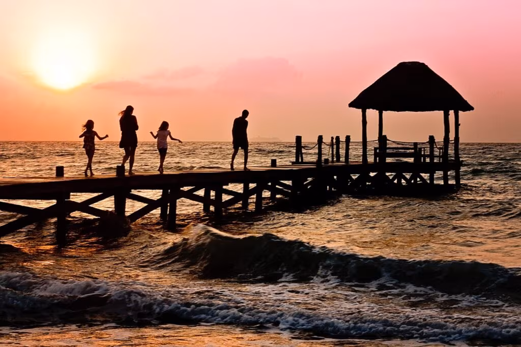 Family walking on a beach at sunset, symbolizing quality time and making memories.