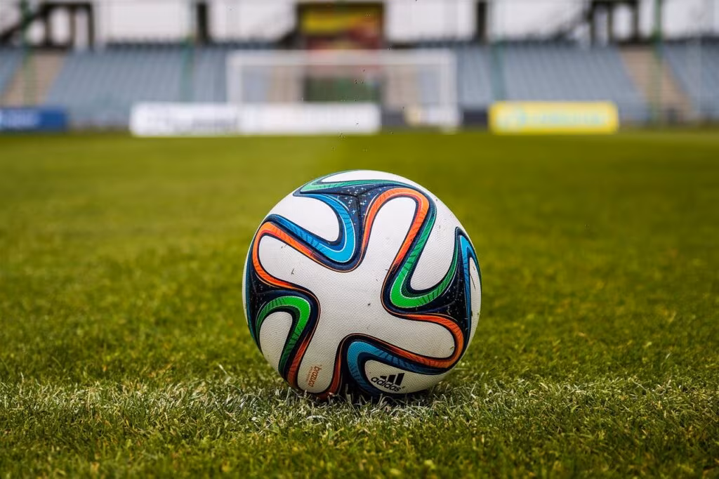 High school football team huddling under stadium lights during an evening game.
