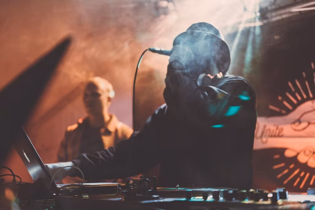 Large stadium filled with concertgoers watching a performer on a massive stage with bright lights.