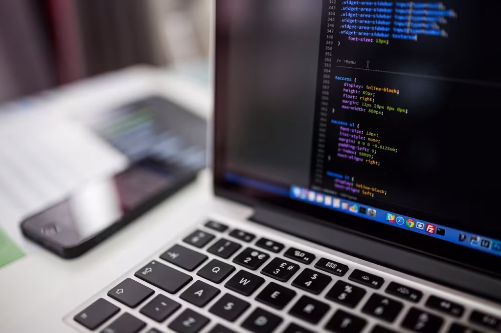 Modern video game development studio with multiple screens showing code and 3D models