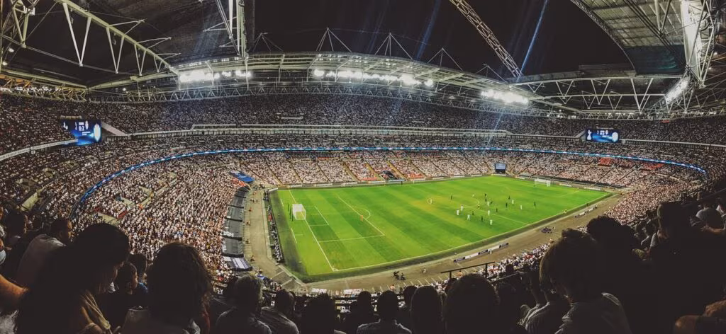 NFL football game action under stadium lights with cheering crowd.