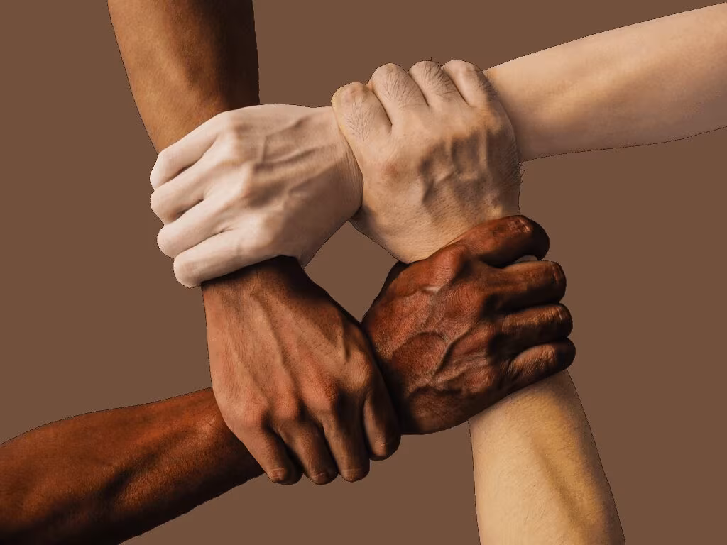 Support group members holding hands, symbolizing community and shared experience in grief.